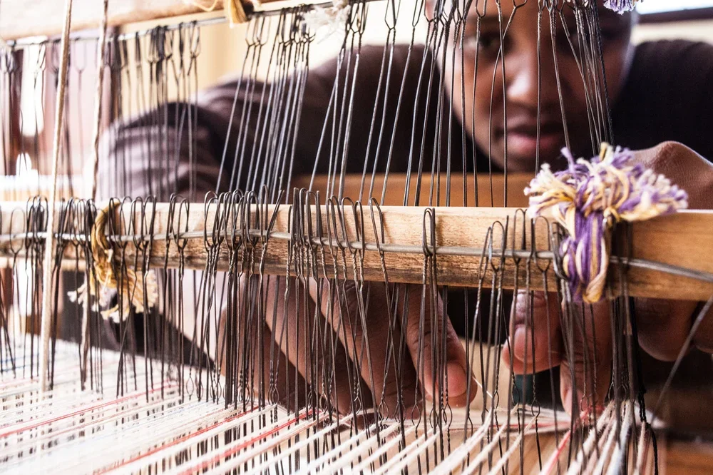An artisan weaving at a loom in a craft workshop.
