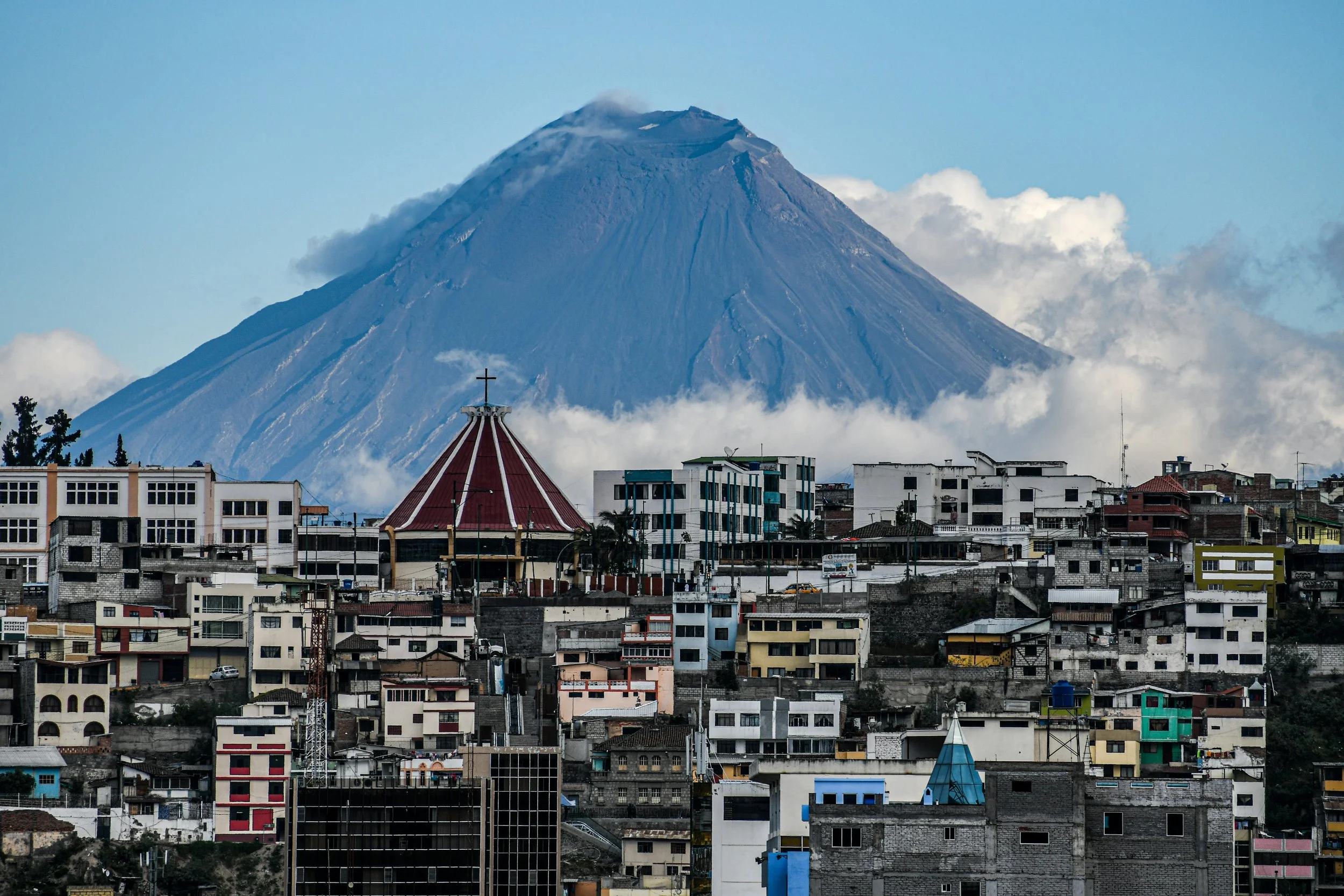 Snow-capped volcano rising above a colorful Andean town in Ecuador