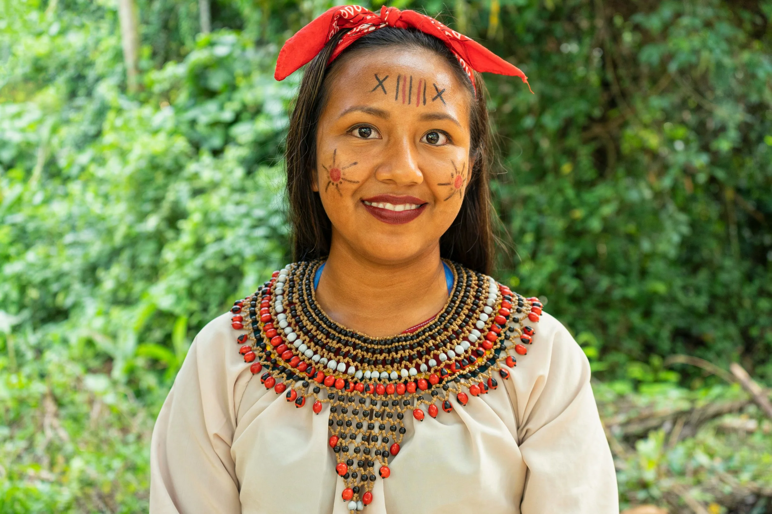 Smiling Indigenous woman with a beaded necklace in the Ecuadorian Amazon