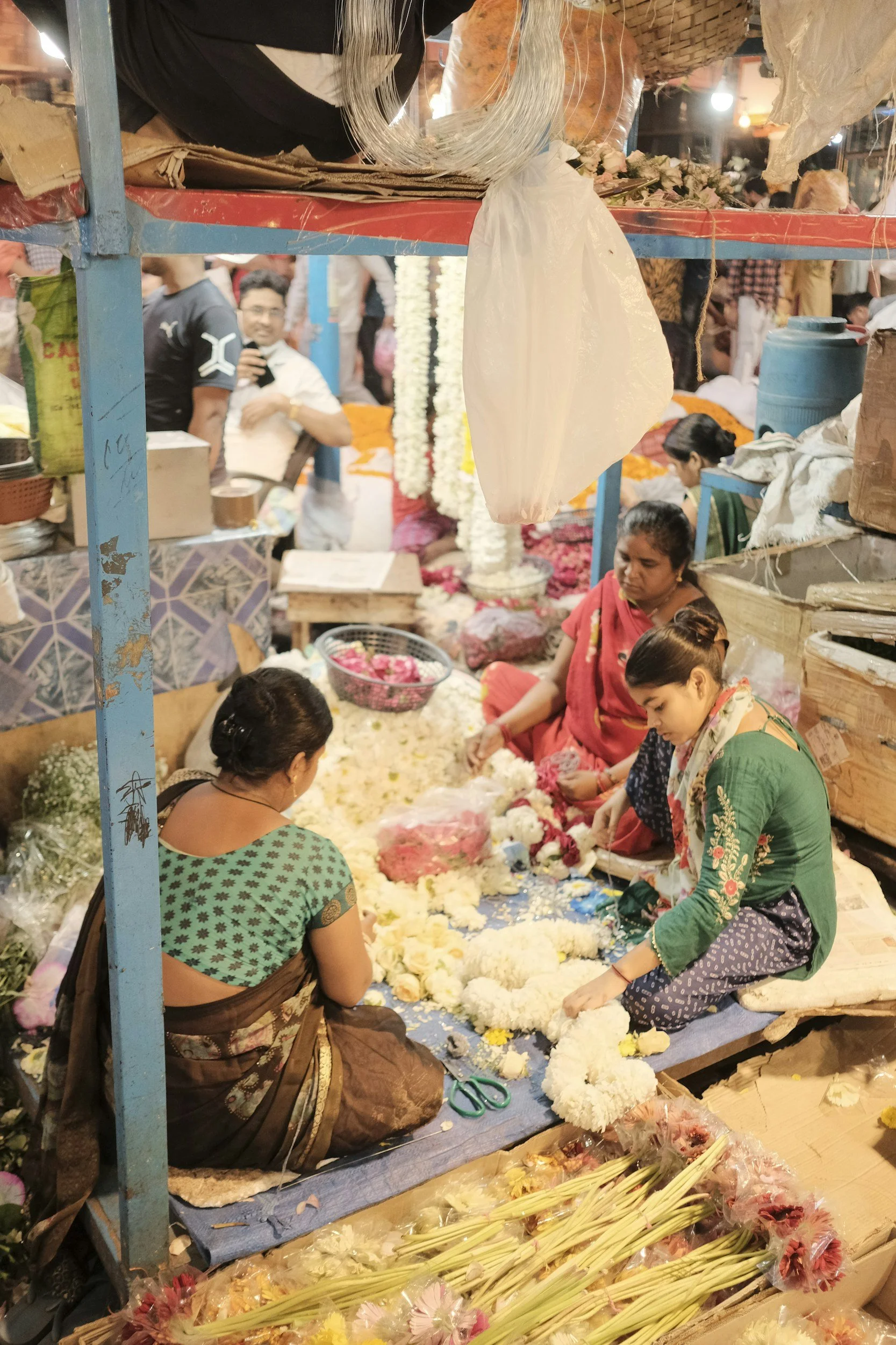 Women in colorful saris sitting together at a street market in India.