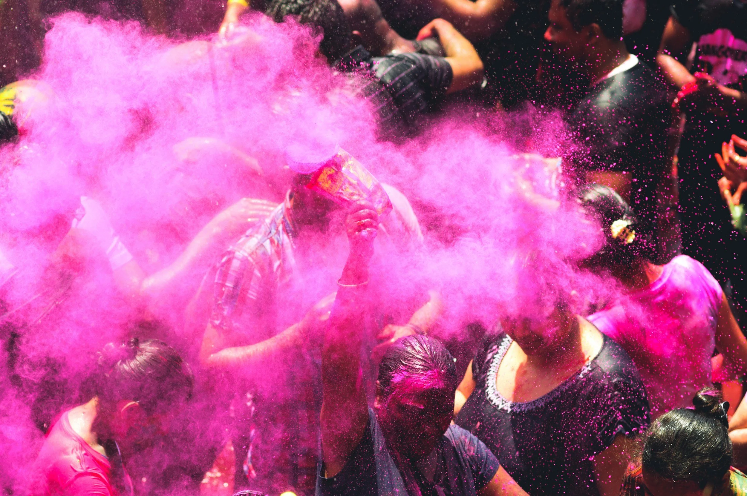A cloud of bright pink powder thrown into the air during Holi.