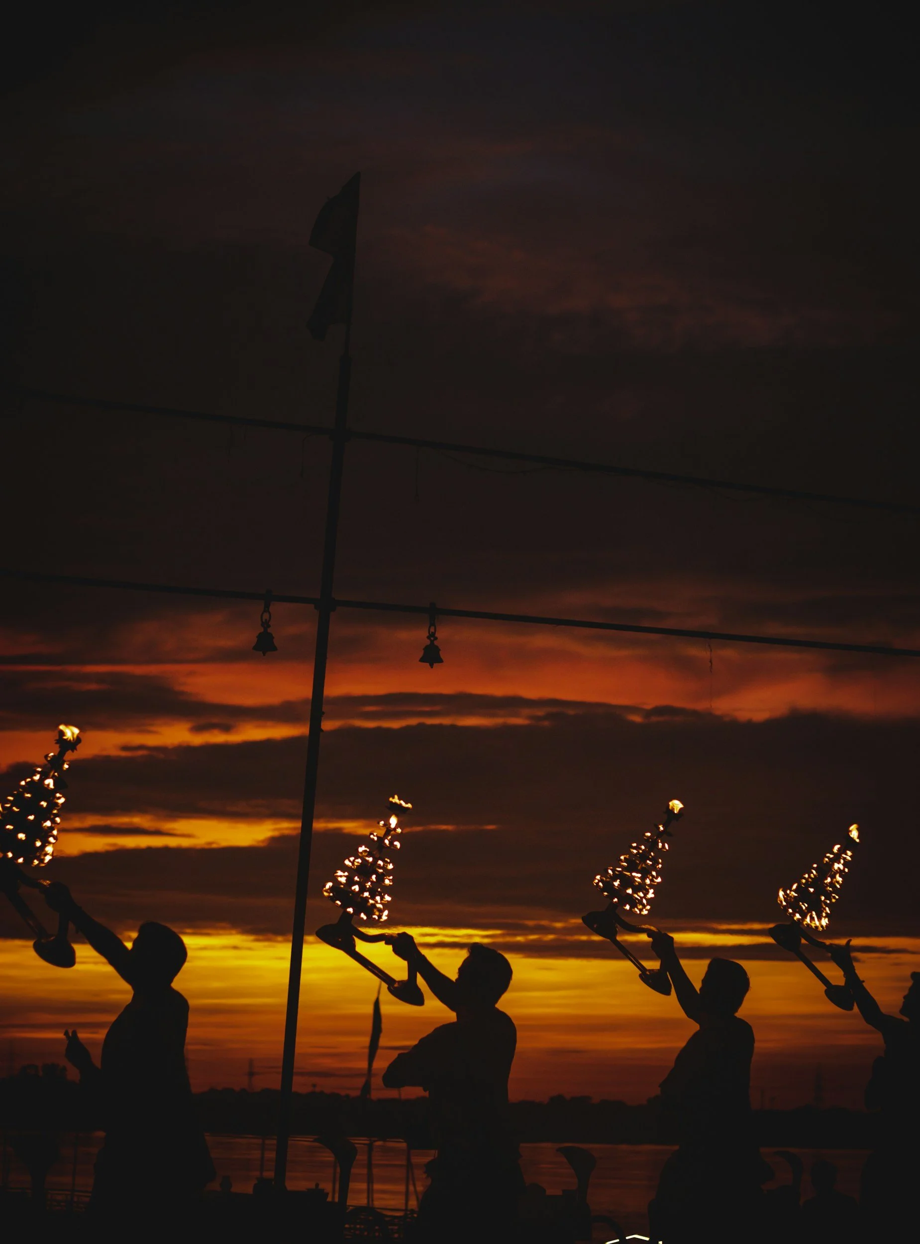 Priests holding fire lamps during the evening Ganga Aarti ceremony at sunset.
