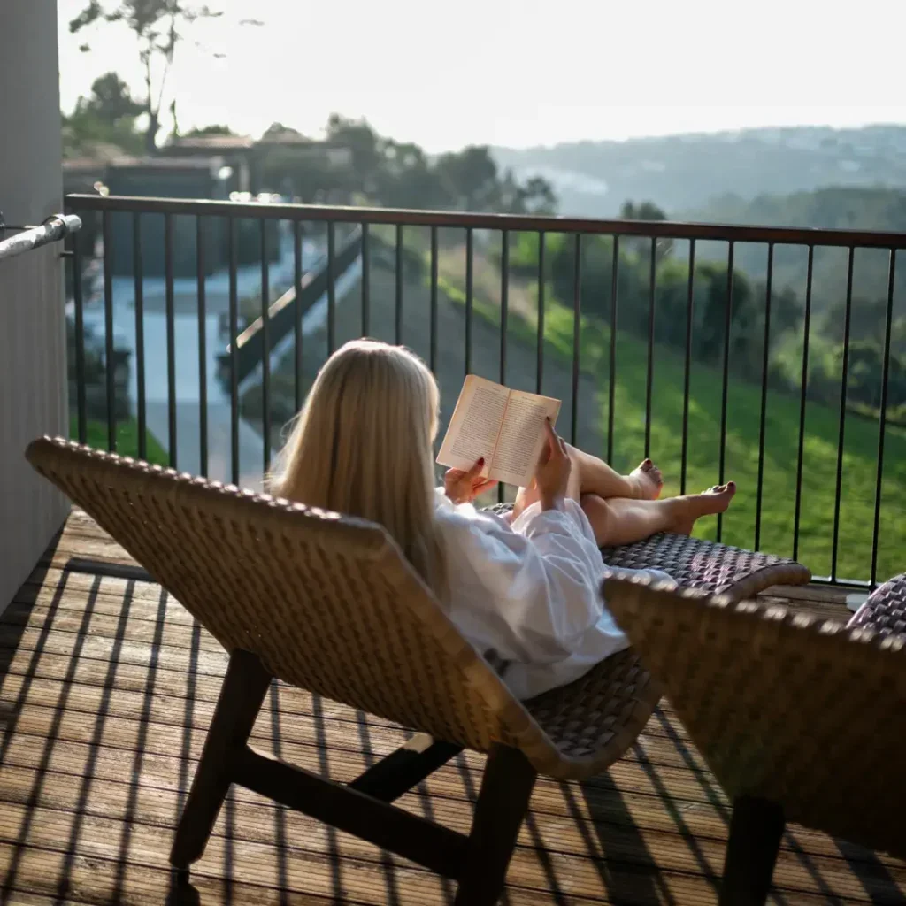 Woman reading on a balcony with views over the Atlantic coast in Ericeira