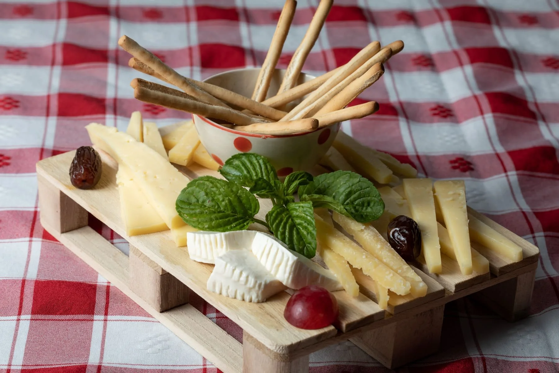 Board of Azorean cheese with breadsticks, grapes and fresh basil