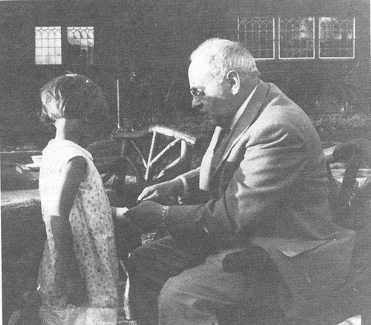 Alfred Adler bandaging the hand of a  child patient, demonstrating his approach to child guidance