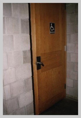 a photo of a wooden door with a blue plaque that features a wheelchair user on it.