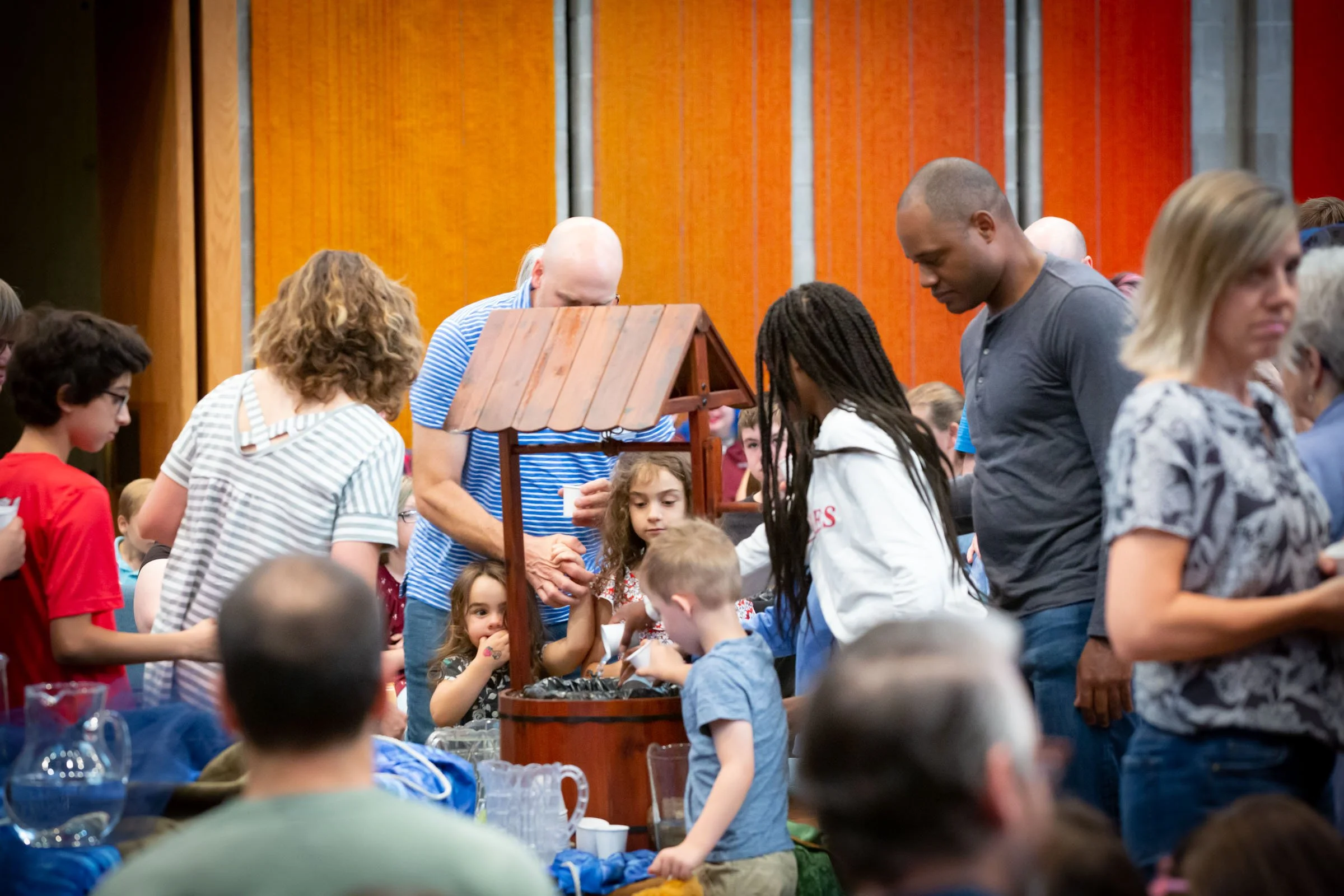 People gathered around a decorative wishing well at an indoor event.