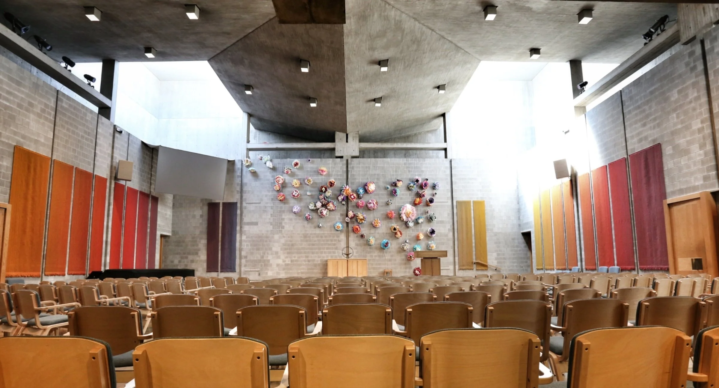 a photo of the sanctuary. taken from the back of the room facing the chancel, this photo highlights the sunlight coming in through the lightwells at the front of the room