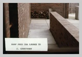 a photo of an exterior ramp leading onto the Susan B. Anthony patio from the lounge. a caption reads "ramp from SBA lounge to S. courtyard"
