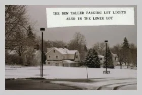 a photo of a snow-covered parking lot with a caption that reads "the new taller parking lot lights also the lower lot".