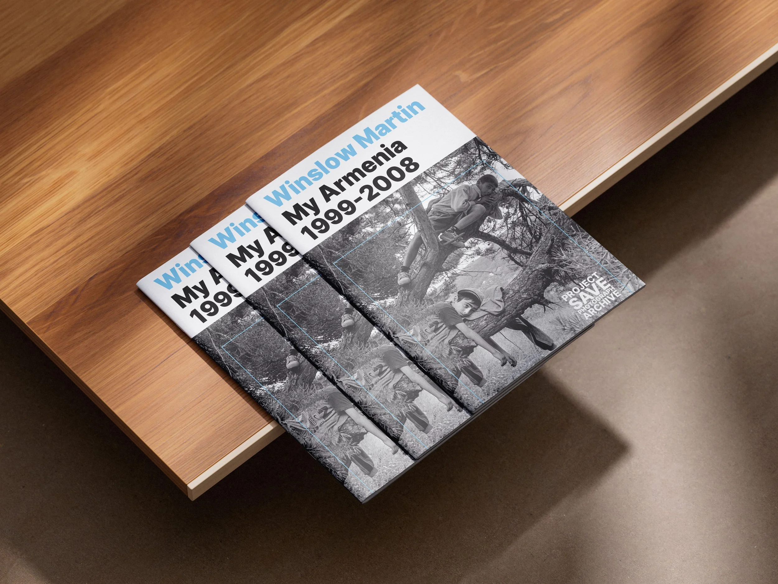 Booklet titled 'Winslow Martin My Armenia 1999-2008' on a wooden table, featuring a black-and-white photograph of children climbing trees.