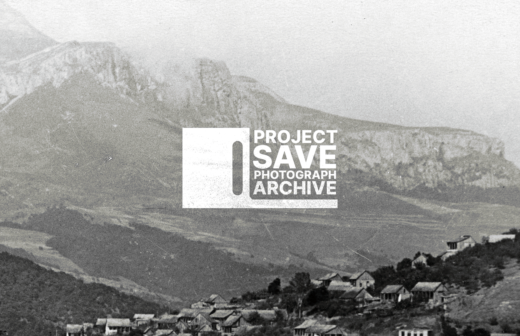 Historical black and white photograph of a mountainous landscape with a village at the base, overlaid with a logo for 'Project Save Photograph Archive'.