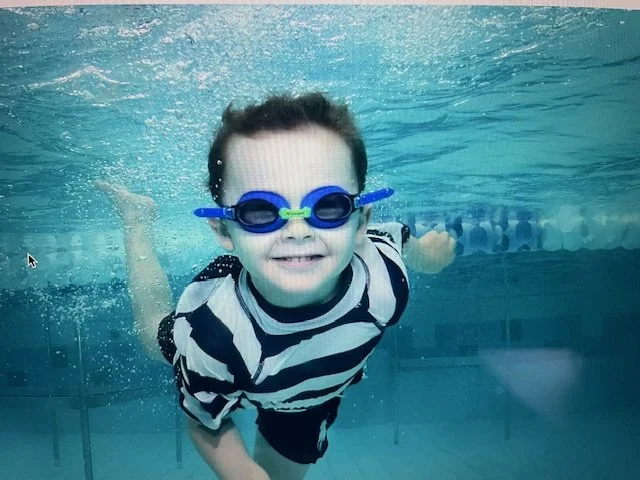 Child learning basic swimming skills during beginner swim lesson.