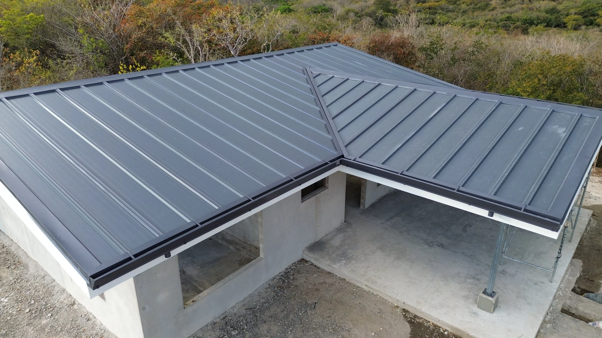 Imagen de un techo de lámina metálica en construcción, sobre una estructura de concreto, con soporte temporal y sin paredes completas.