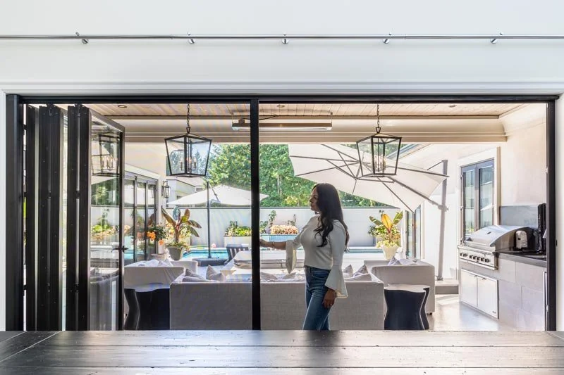 Indoor-outdoor living in San Diego with Vanishing Screens retractable door screen connecting kitchen to patio with grill and umbrellas.
