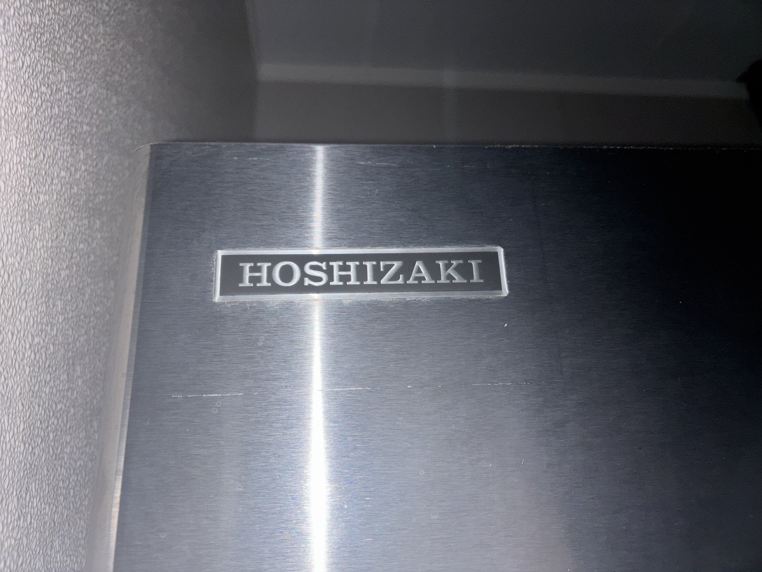 Close-up of a Hoshizaki equipment logo on a stainless steel surface