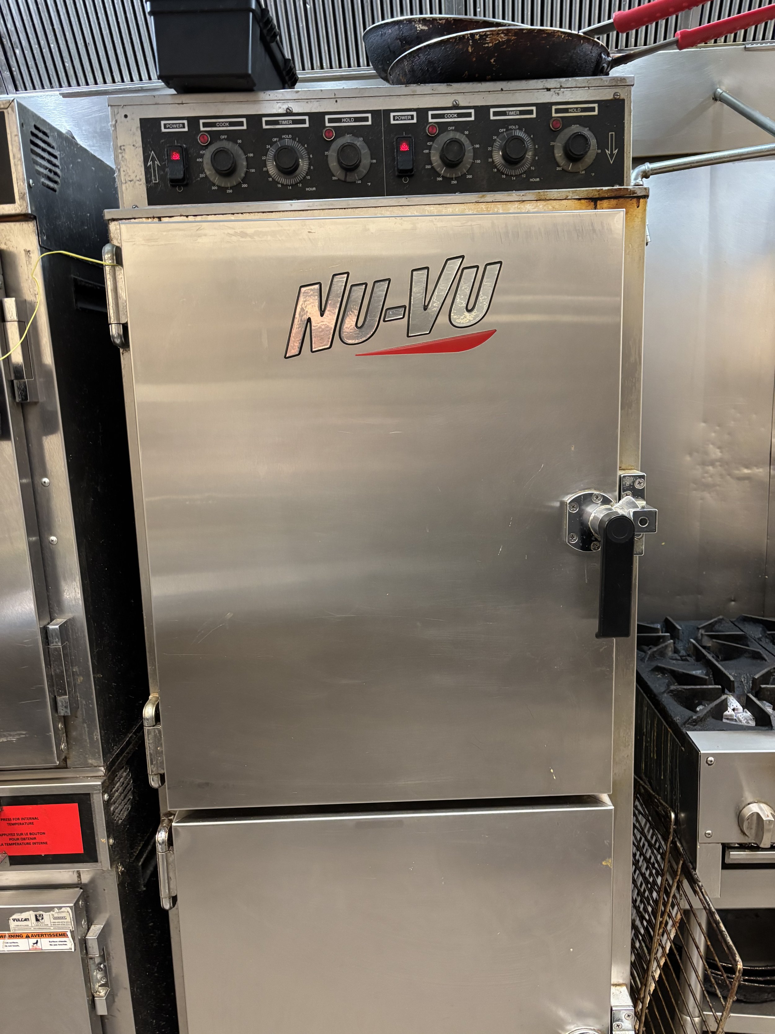Commercial Nu-Vu oven with controls, stainless steel finish, and additional kitchen equipment visible.