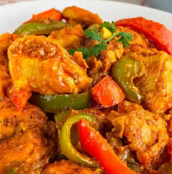 Chicken curry with bell peppers and cilantro garnish on a plate.