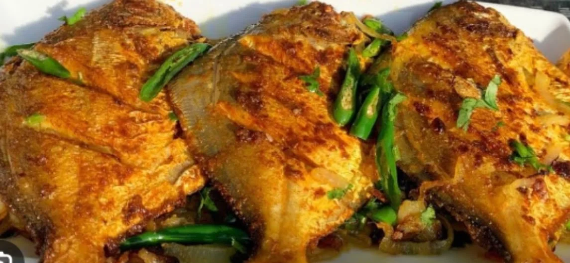 Grilled fish with green chilies and herbs on a plate.