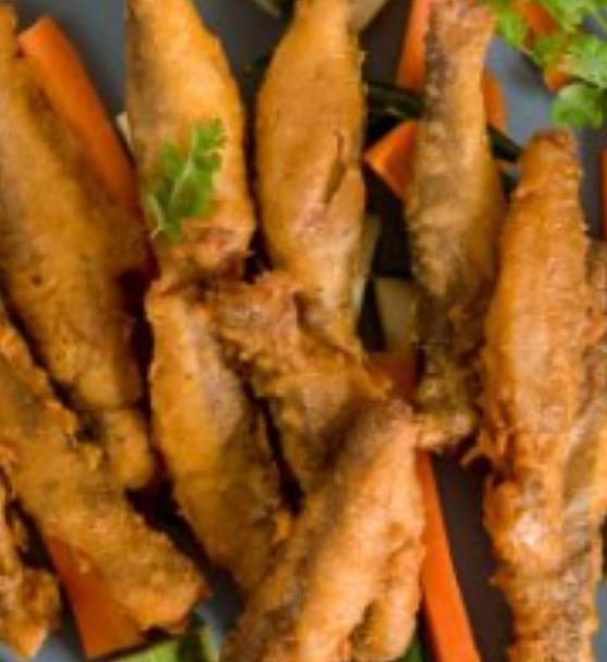 Close-up of fried fish fillets served with vegetables and garnished with parsley.