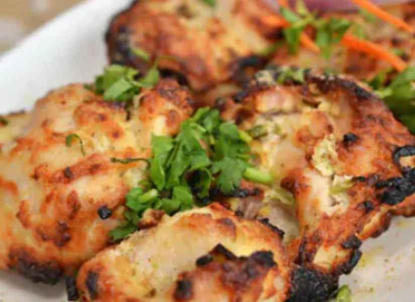 Grilled chicken pieces garnished with cilantro on a white plate.