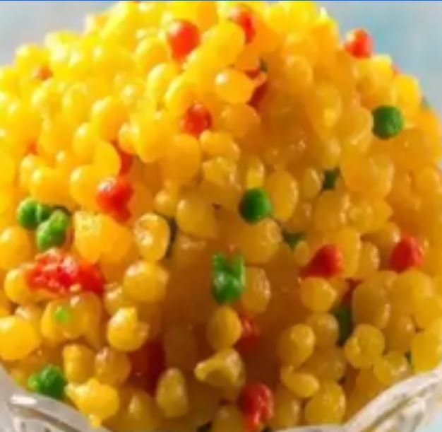 Close-up of colorful ice cream pellets with yellow, red, and green sprinkles.