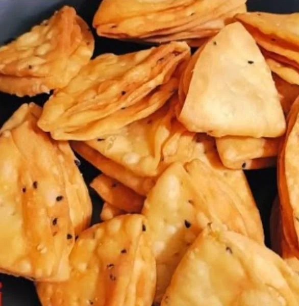 Plate of crispy fried snacks, likely Indian mathri, with sesame seeds.