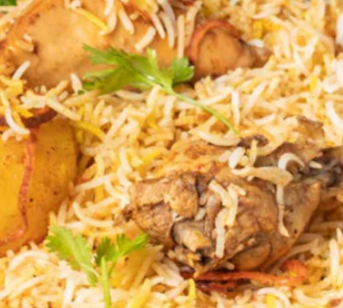 Plate of chicken biryani with rice, potatoes, and cilantro garnish.