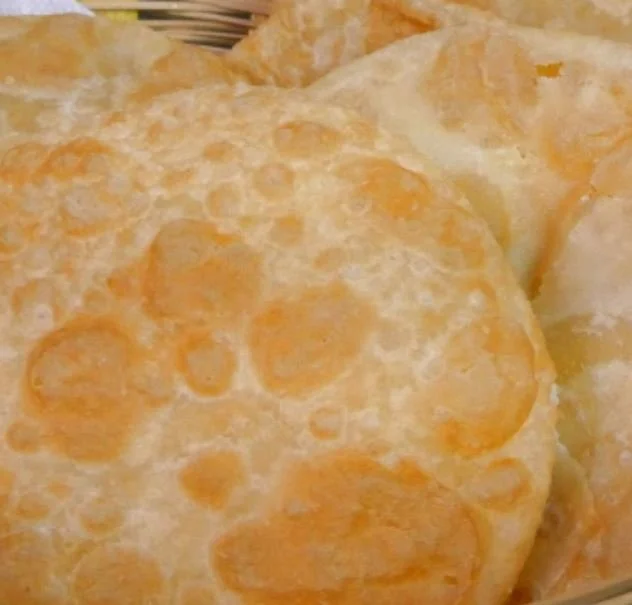 Close-up of golden brown fried bread, resembling thick tortillas.