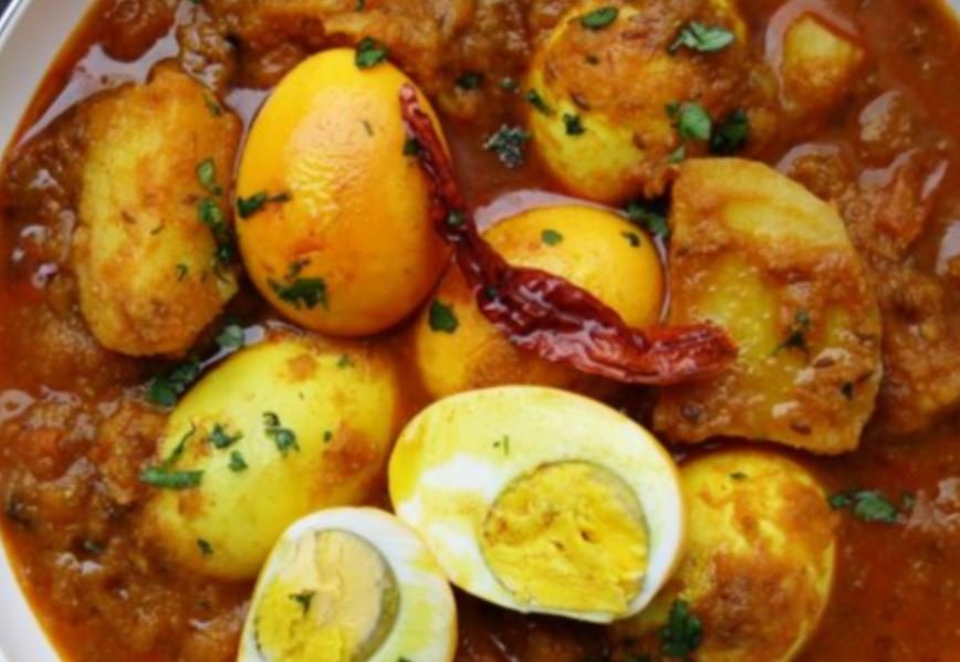 Indian egg curry with boiled eggs, potatoes, spices, and garnished with cilantro in a spicy tomato-based sauce.