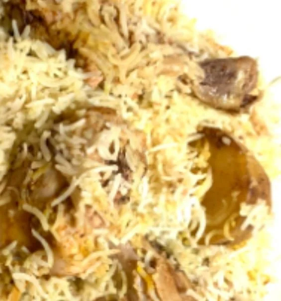 Close-up of biryani rice with pieces of meat and spices.