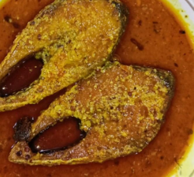 Two cooked fish slices in a red curry sauce.