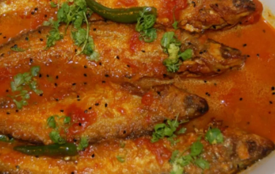 Fried fish in spicy tomato sauce with green chilies and cilantro garnish.