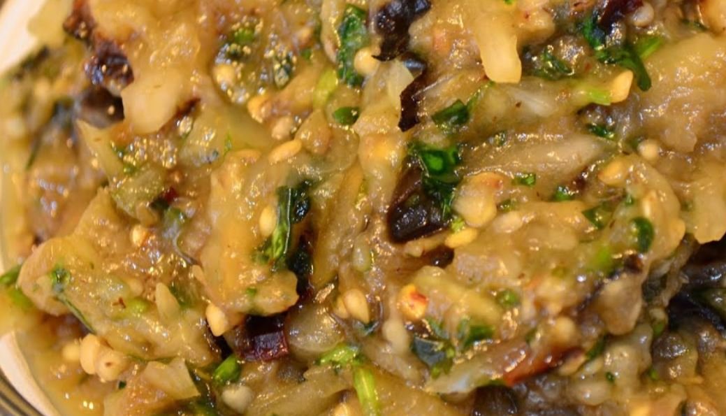 Close-up of chopped and mixed roasted eggplant dish with herbs and seeds.