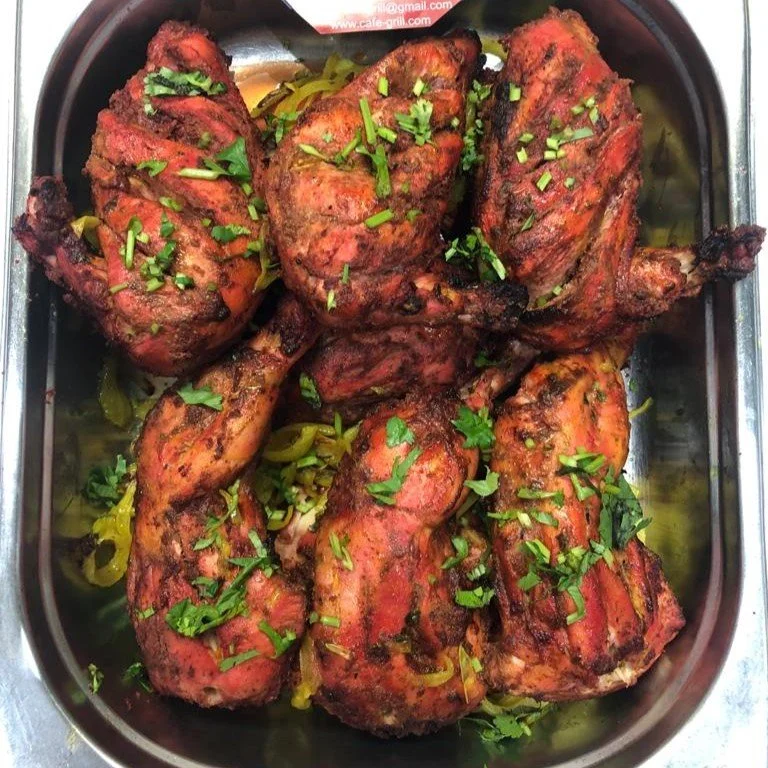 Roasted chicken legs garnished with herbs in a metal tray