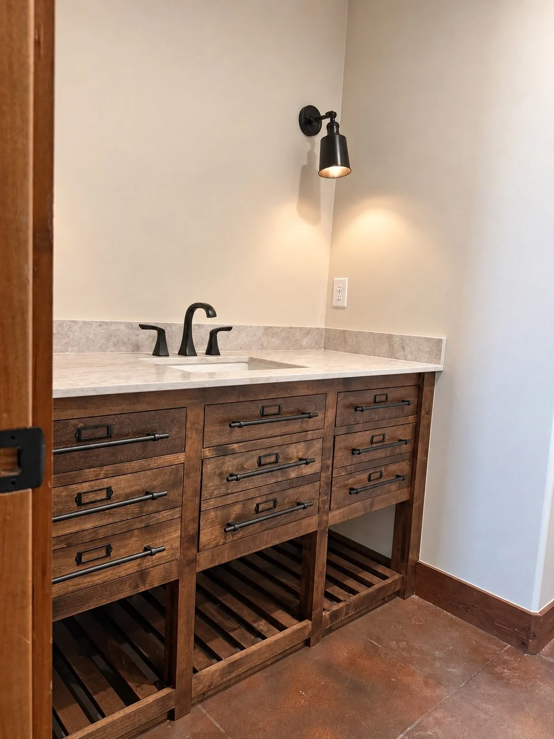 Furniture-style wood bathroom vanity with drawers, open slatted storage, a light countertop and dark fixtures.