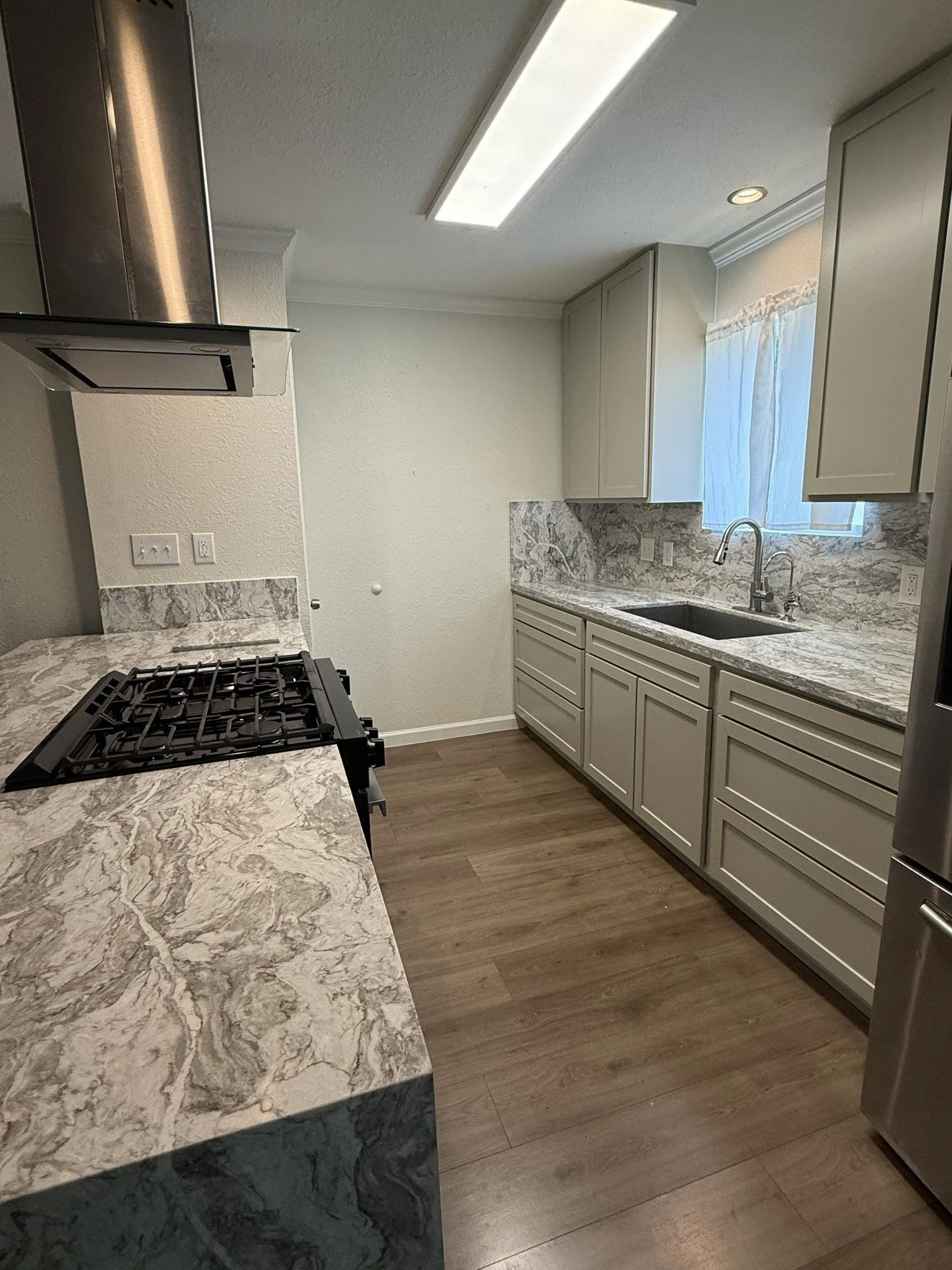 A bright kitchen with clean cabinet lines and warm wood-look flooring.
