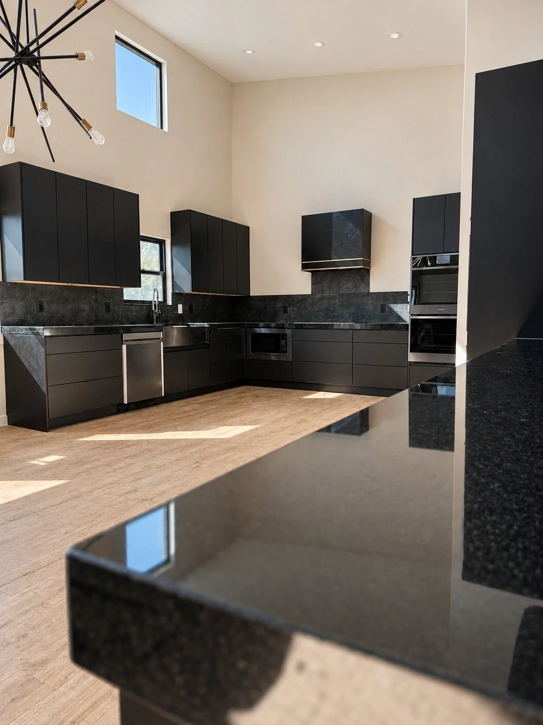 Matte black custom kitchen cabinetry with dark counters and stainless steel appliances.