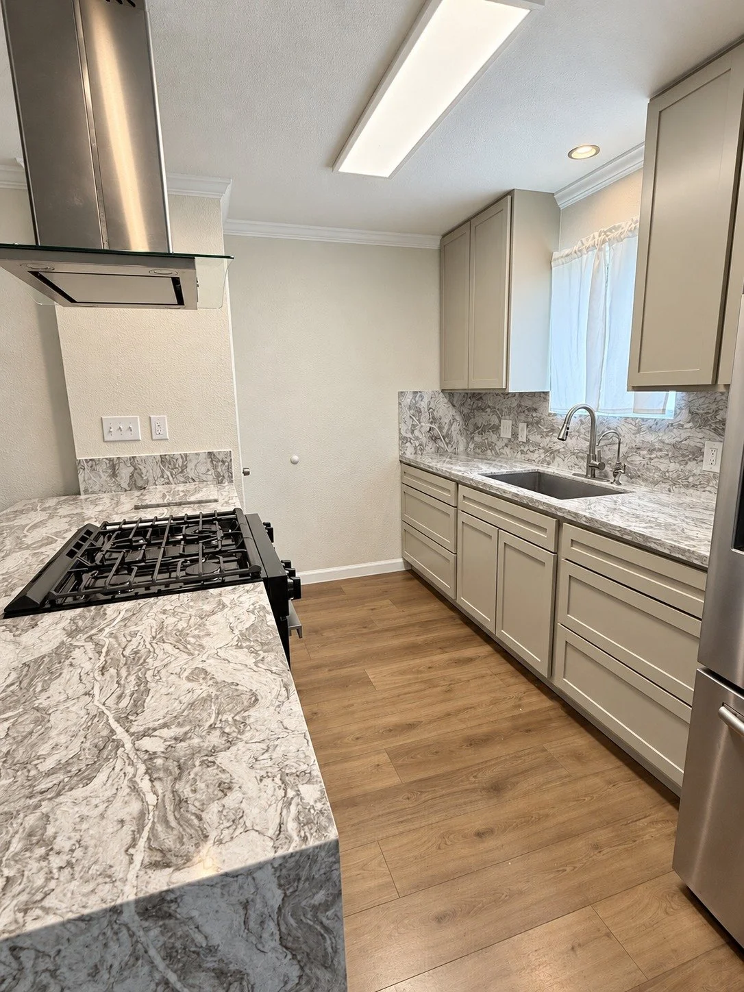 A bright kitchen with clean cabinet lines and warm wood-look flooring.