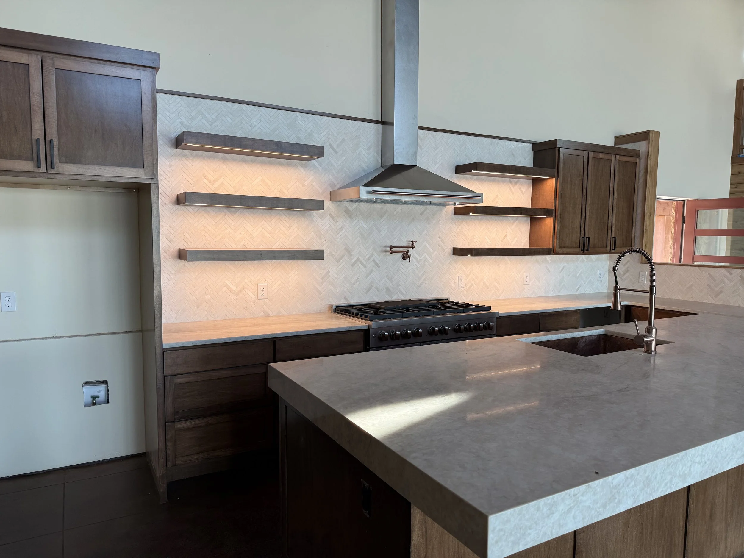 Modern kitchen with wooden cabinets, a gas stove, a sink with a faucet, and a decorative backsplash.
