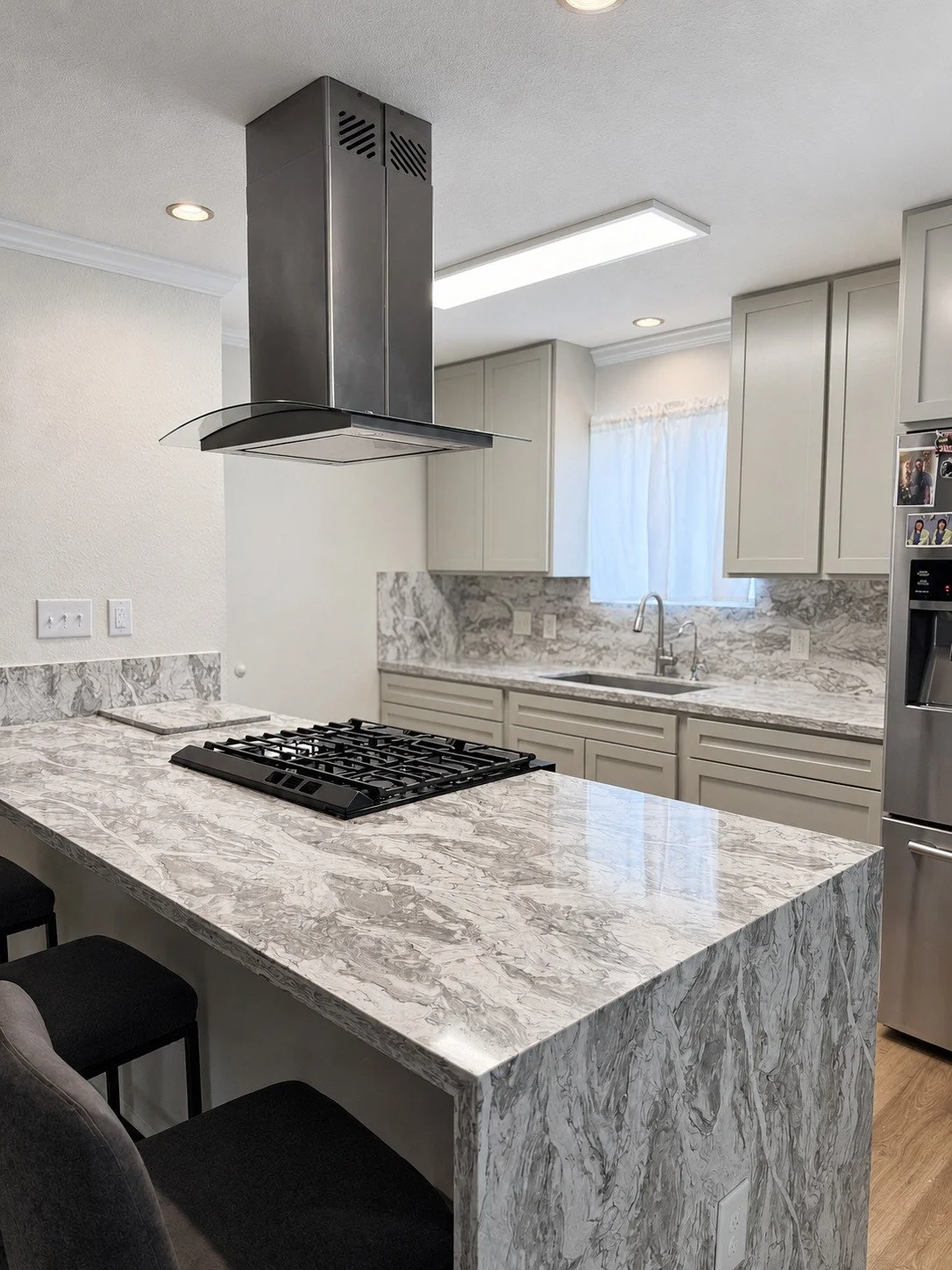 Soft Contrast Kitchen — light cabinetry, patterned surfaces, and a striking dark range hood.