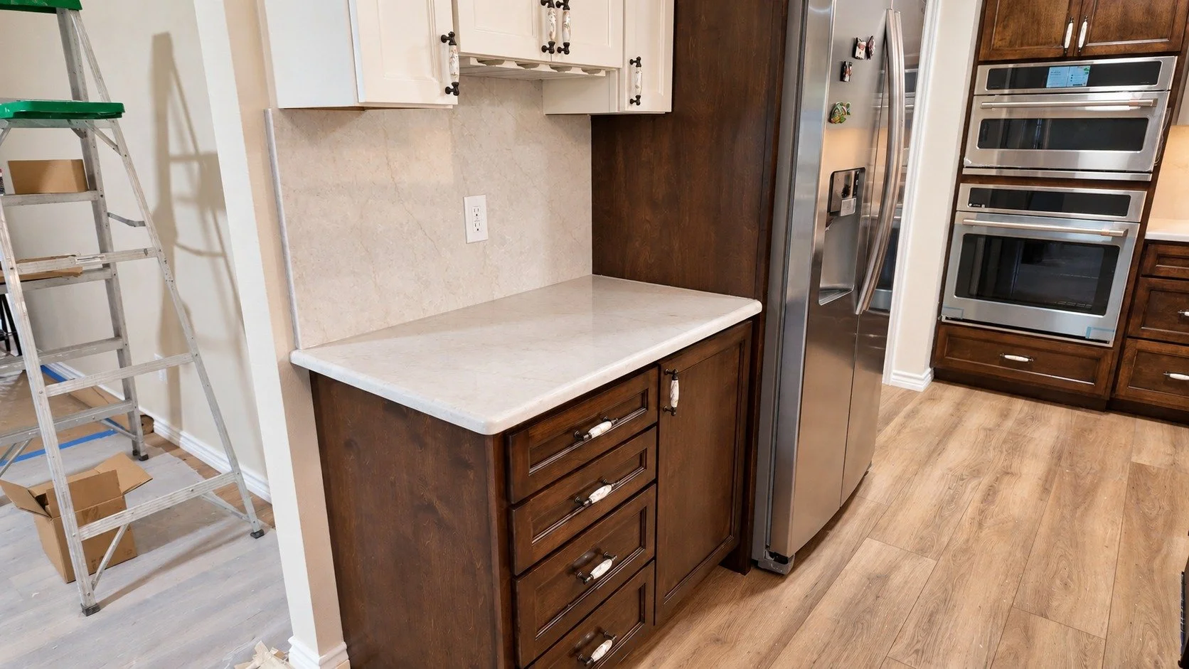 Glass-front cabinetry and a built-in counter beside the ovens.