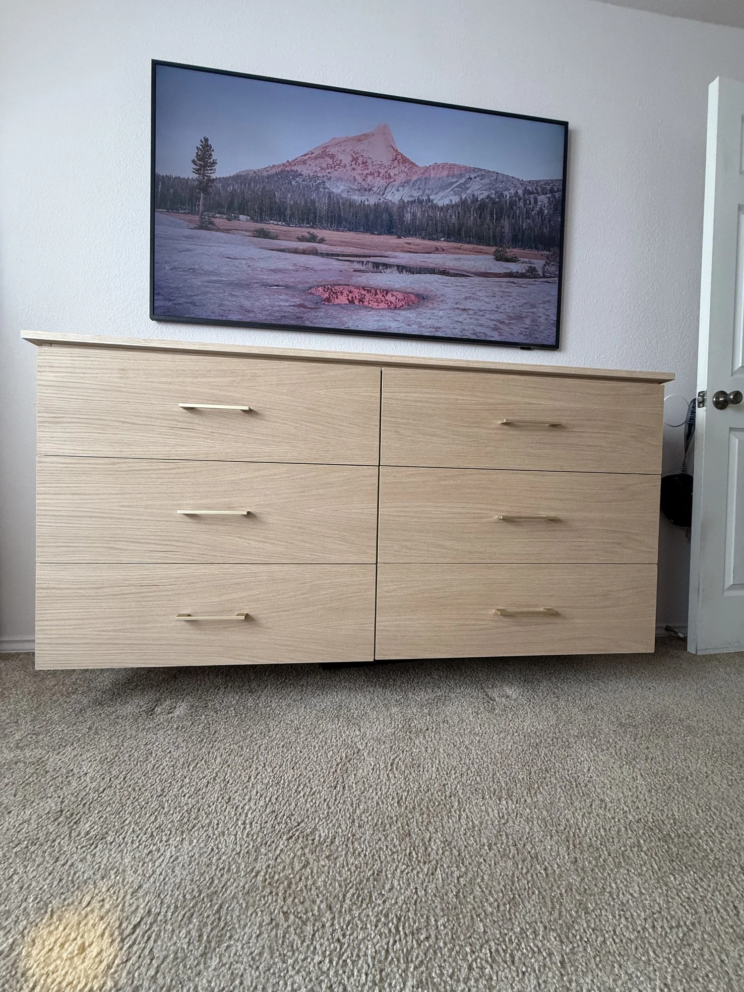 Custom light wood drawer storage beneath a wall-mounted television.