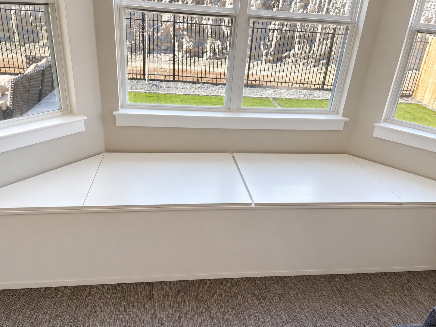 White built-in window bench with storage fitted beneath a bay window.