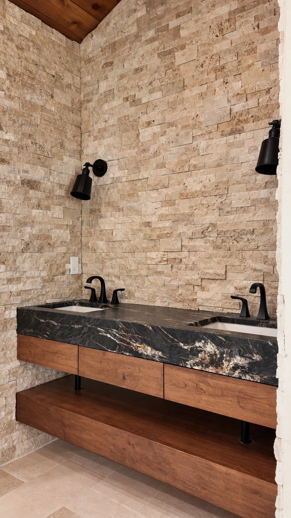 A floating double vanity against a textured stone wall.