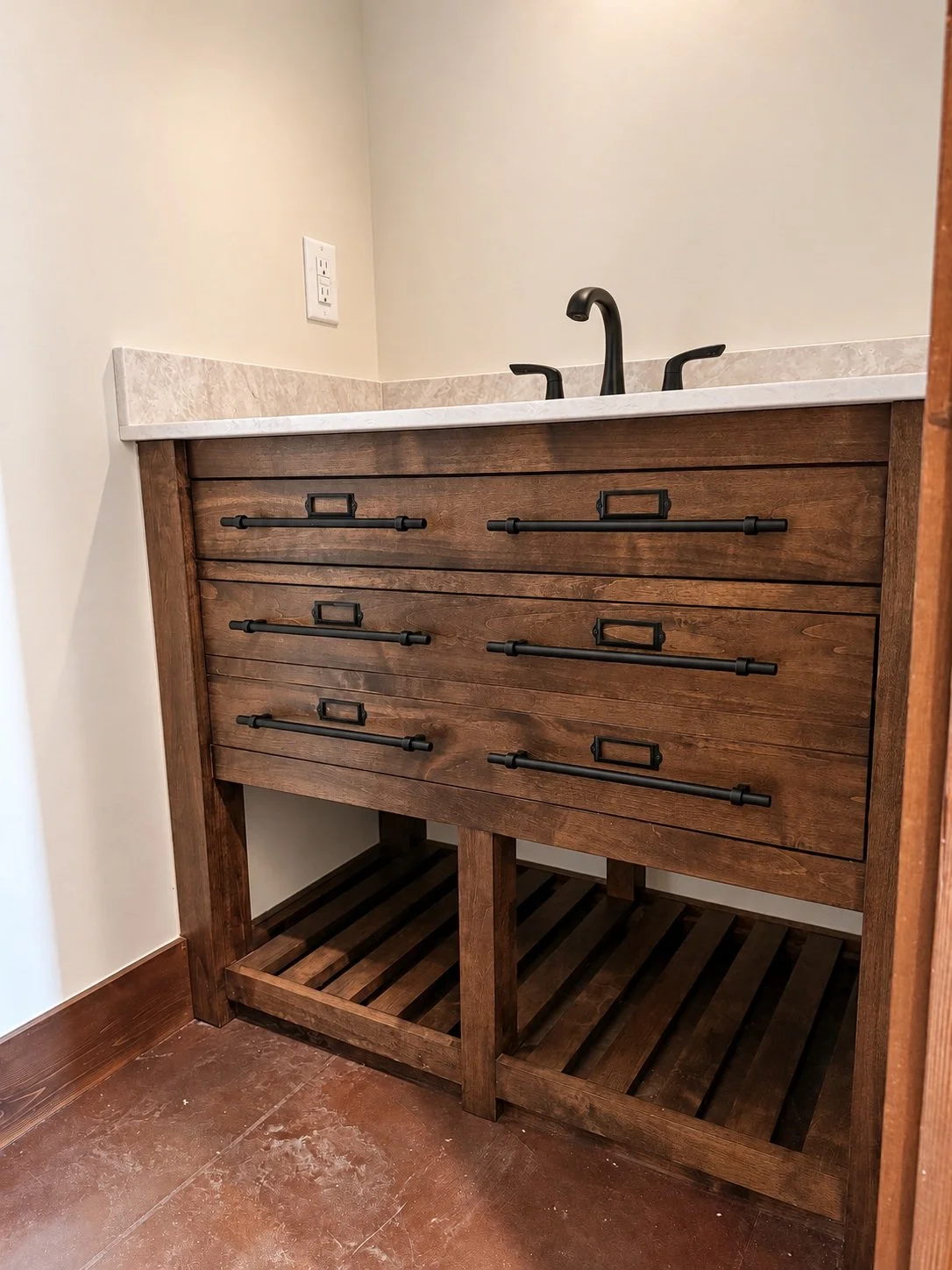 Rustic wood single vanity with black bar pulls and label holders, a black faucet, and open shelves beneath the drawers.