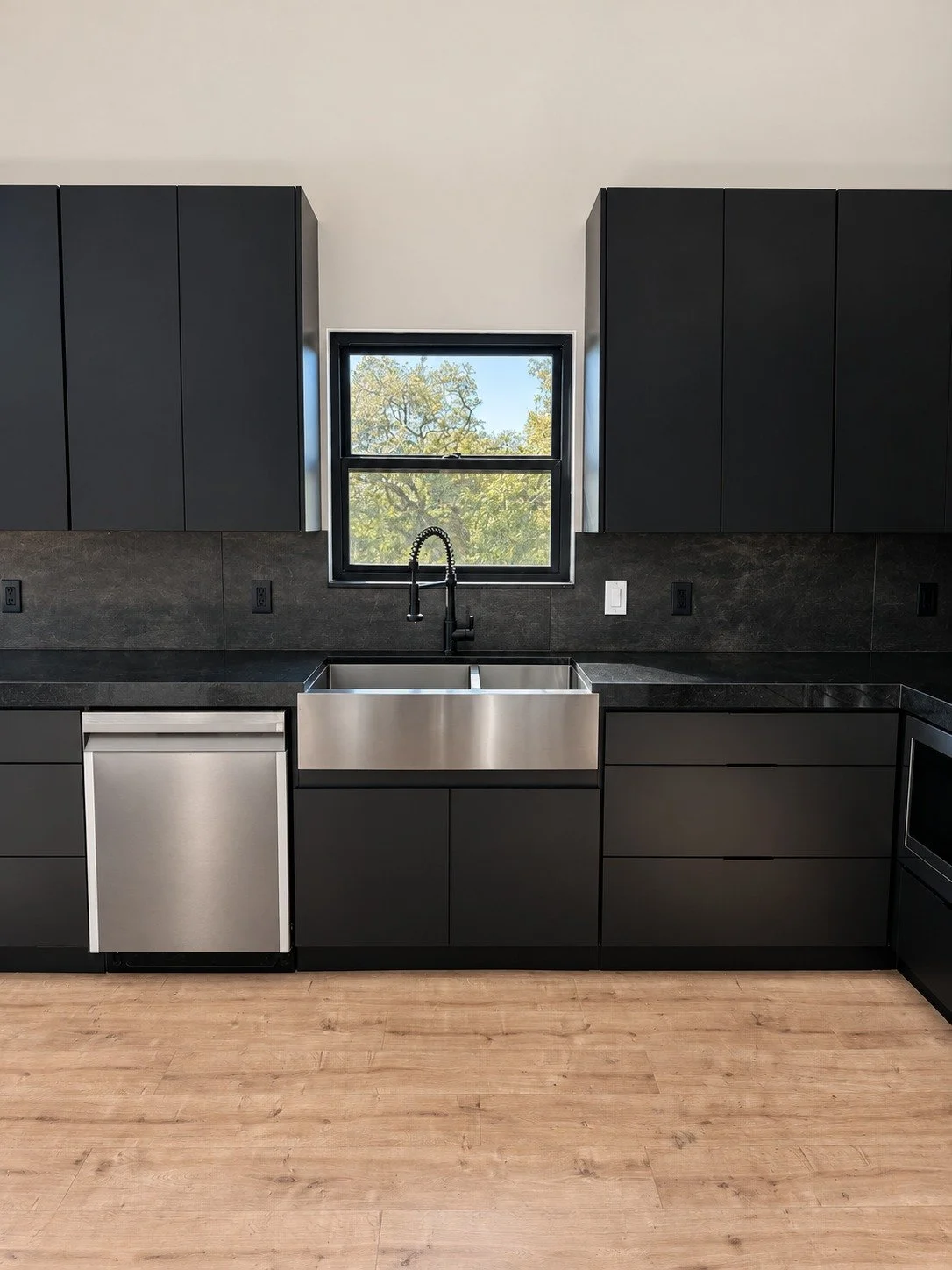 The sink wall with black cabinetry and stainless steel appliances.