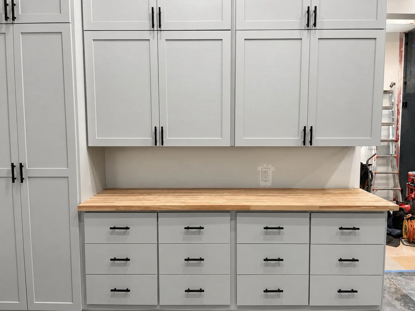 A closer view of gray cabinet doors and drawers with black handles and a wood countertop.