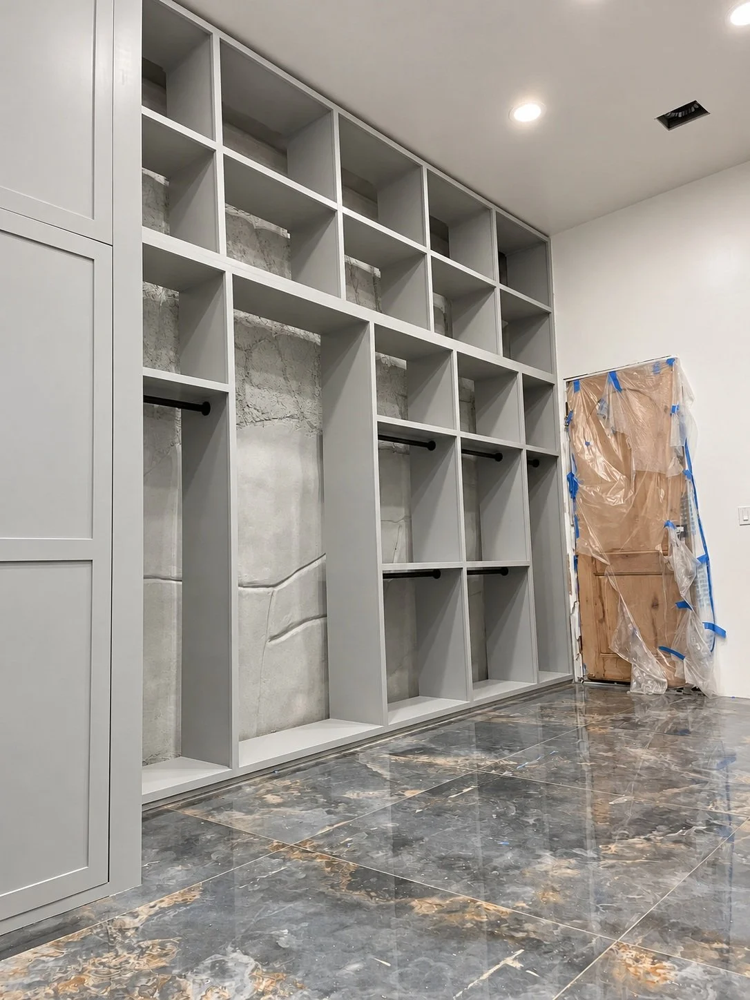 Open closet shelving with divided compartments and hanging rods, shown during installation.
