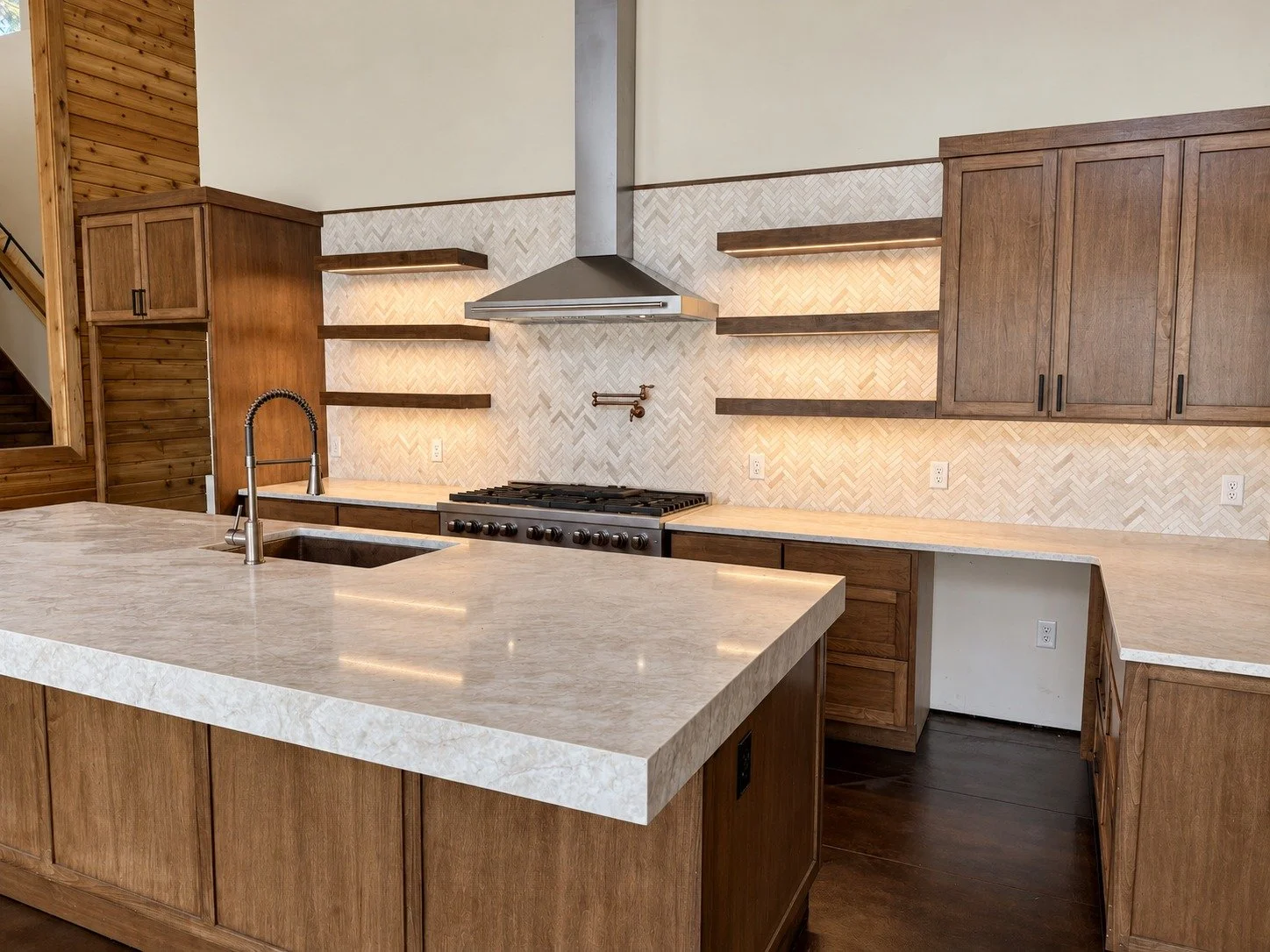 A generous kitchen island framed by custom cabinetry and open shelving.